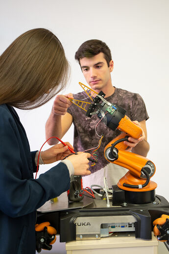 Zwei Studierende arbeiten an dem Roboterarm