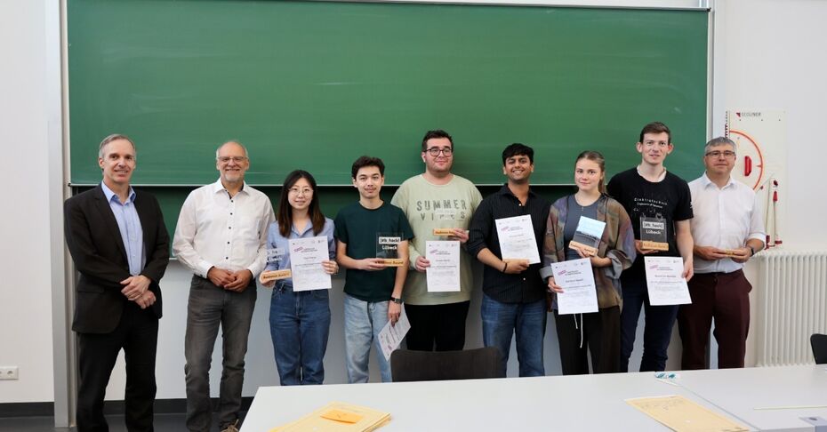 Die Gewinner*innen des Hackathons stehen mit ihren Auszeichnungen vor einer grünen Tafel