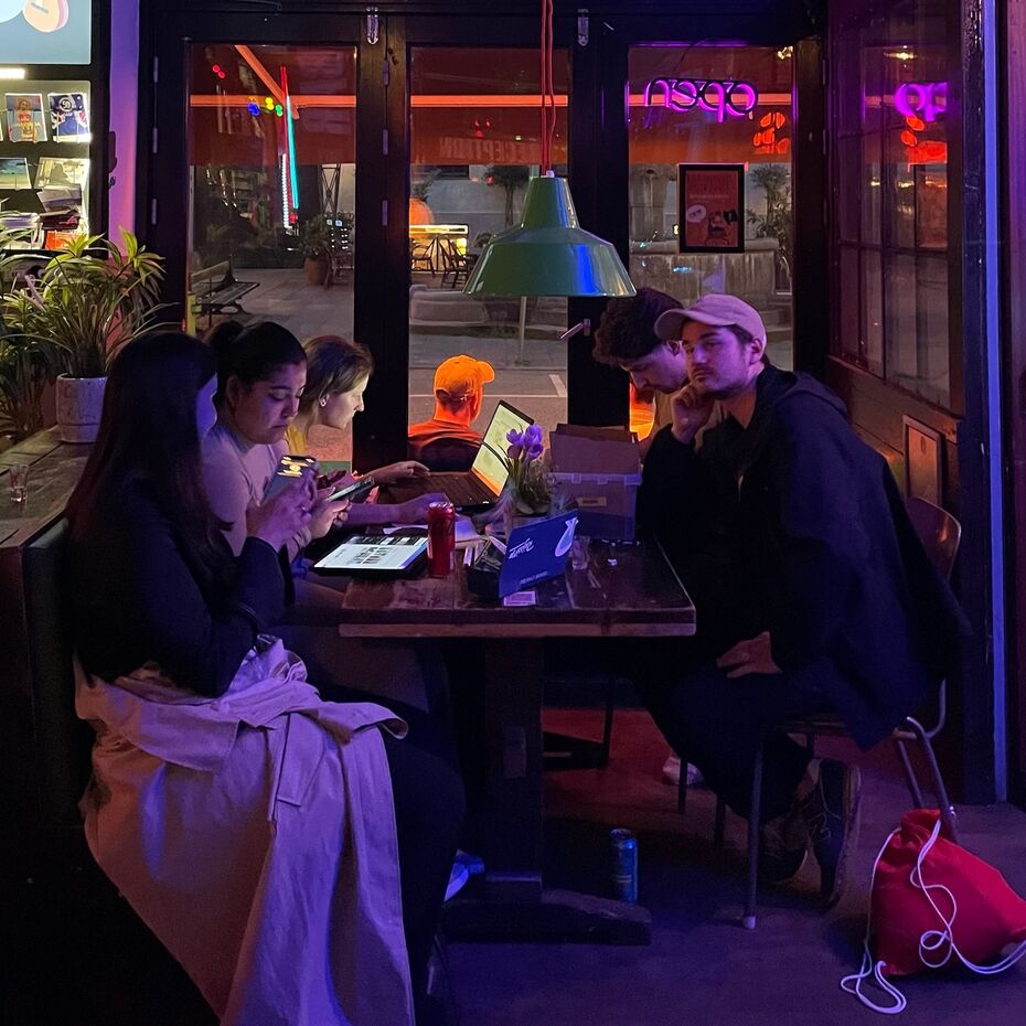 Foto sitzen in einer Bar mit pinkem Licht an einem Tisch