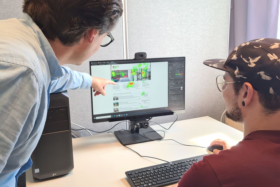 Personen arbeiten an einem Bildschirm, auf dem eine Heatmap von einer Website zu sehen ist. Diese Heatmap wurde mit der Eye-Tracking-Brille aufgenommen.
