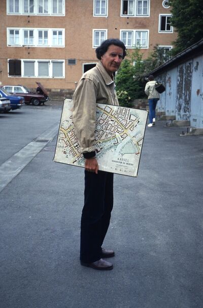 Lucius Burckhardt hält einen Bebauungsplan von Kassel unter dem Arm.