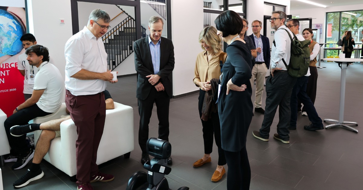 Gruppe betrachtet mobilen Roboter im Hochschulfoyer