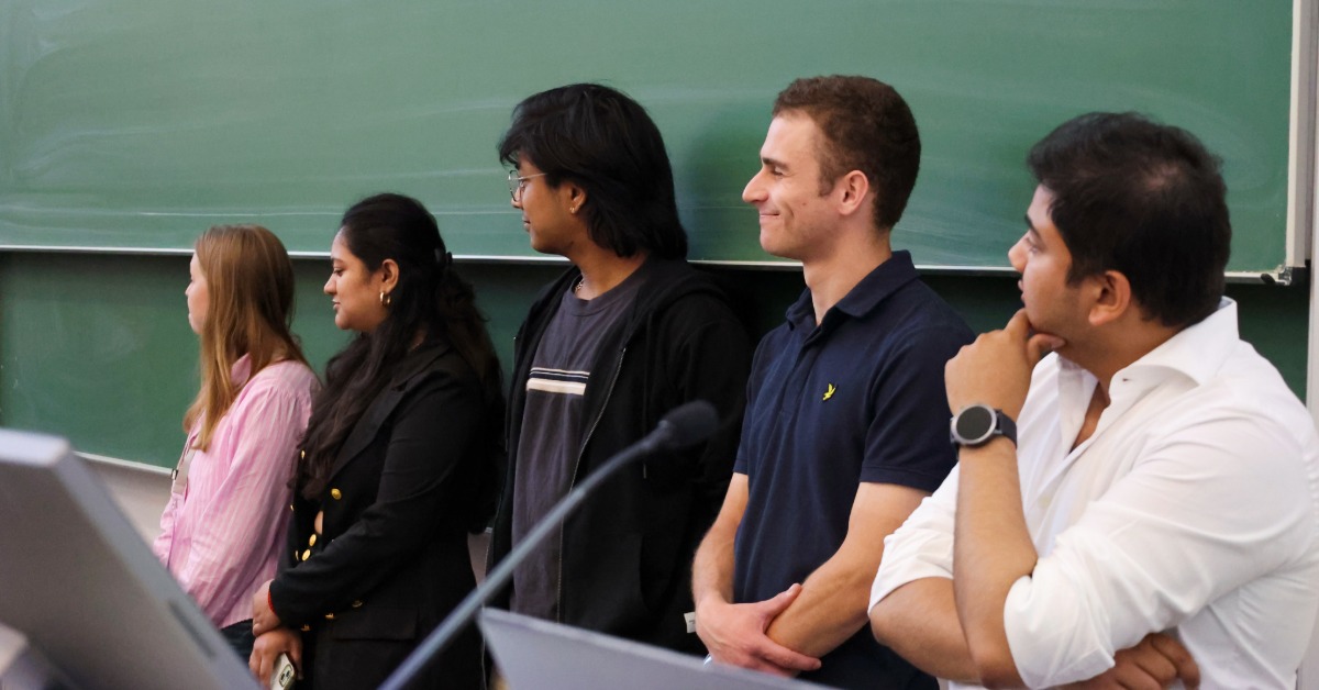 Fünf Personen stehen nebeneinander vor einer grünen Tafel im Hörsaal
