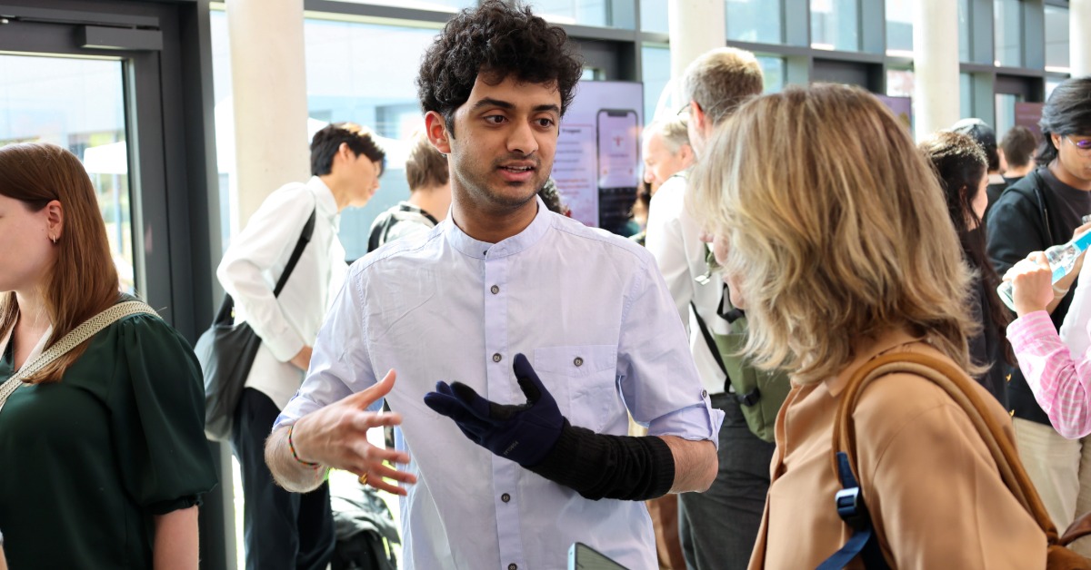 Ein Mann mit schwarzem Handschuh ist in einem lebhaften Gespräch mit einer Frau im Foyer