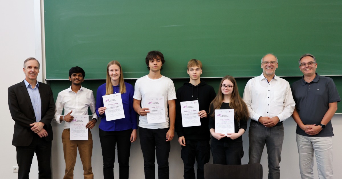 Ein Team steht mit den Organisatoren und Zertifikaten in den Händen vor einer grünen Tafel