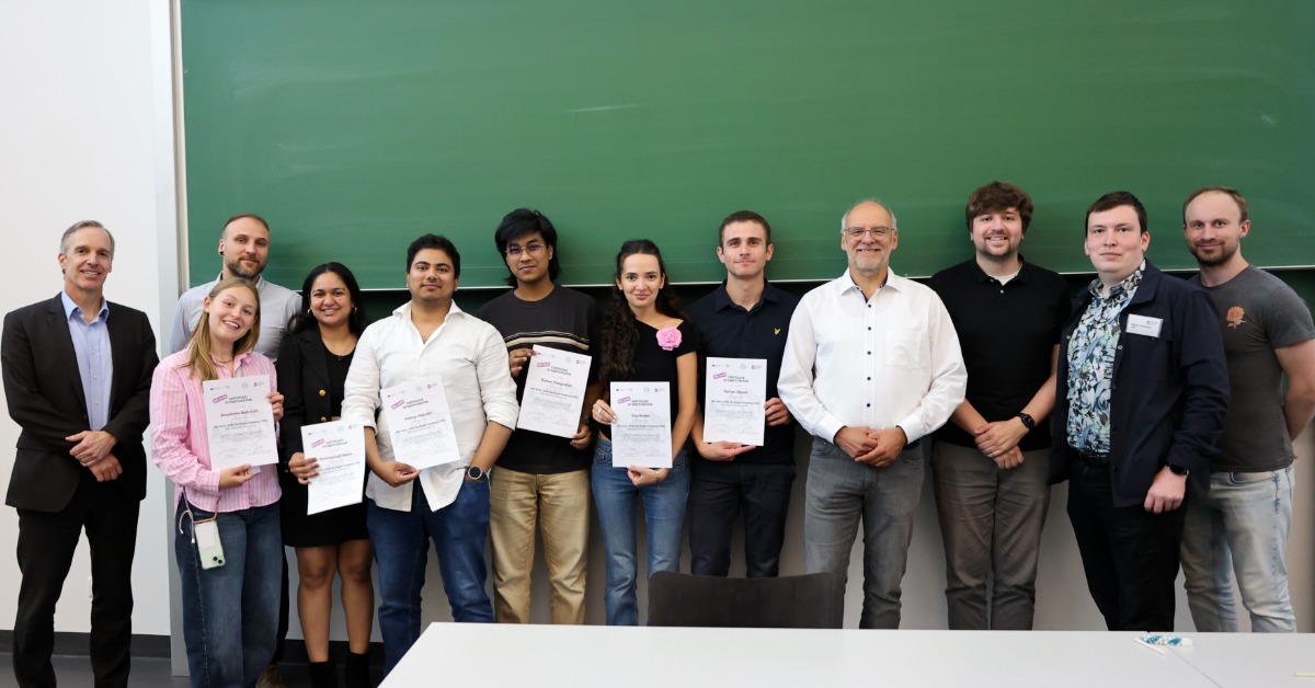 Ein Team steht mit den Organisatoren und Zertifikaten in den Händen vor einer grünen Tafel
