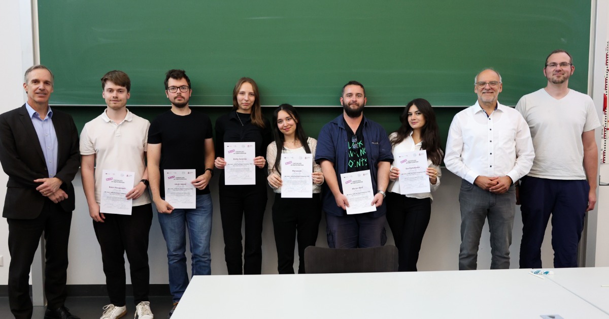 Ein Team steht mit den Organisatoren und Zertifikaten in den Händen vor einer grünen Tafel