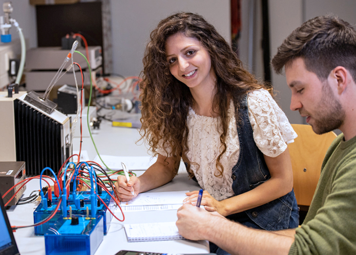 Zwei Studierende sitzen an einem Tisch und arbeiten