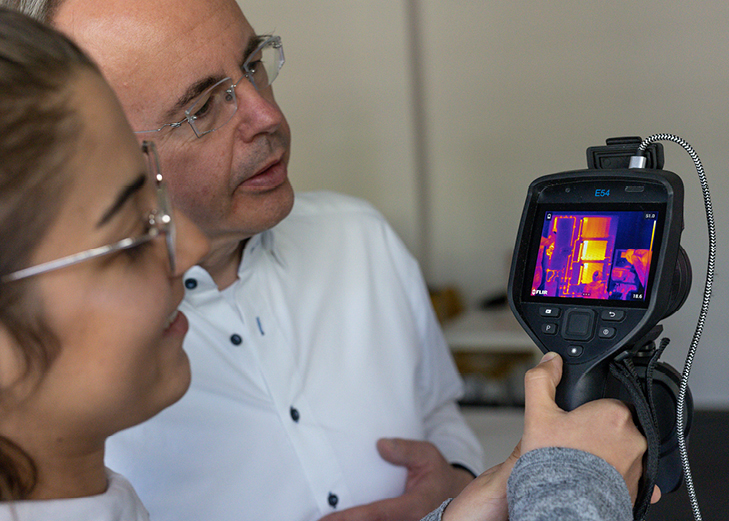 Zwei Personen gucken auf Bildschirm einer Thermografiekamera