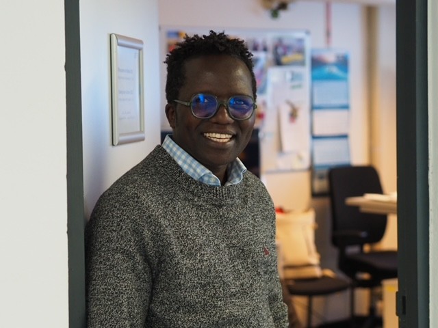 Mann steht lächelnd an offener Bürotür