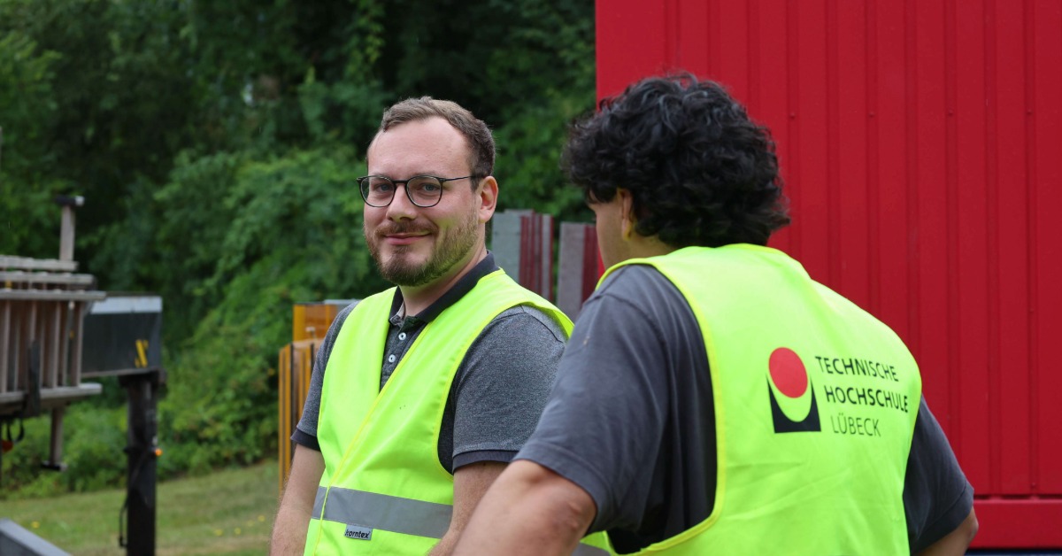 Zwei Studenten vor einem roten Container