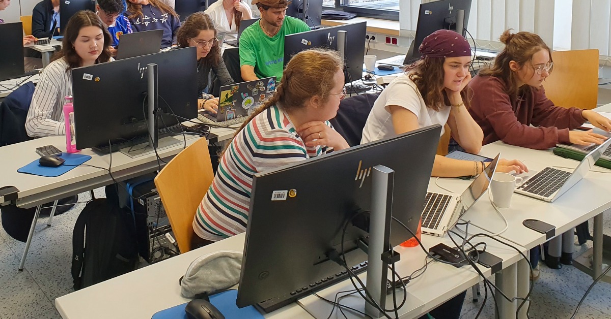 Studierende sitzen hinter Bildschirmen.