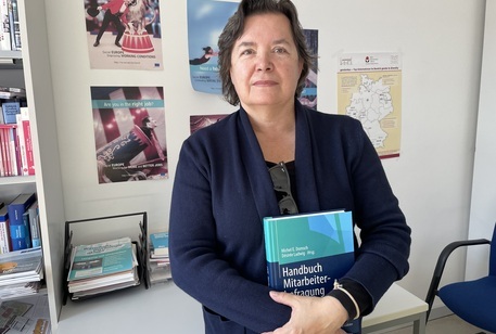Frau hält das Buch „Handbuch Mitarbeiterbefragung“ in den Händen.