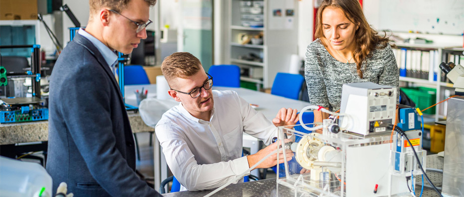 Drei Personen arbeiten im Labor an einem technsichen Gerät