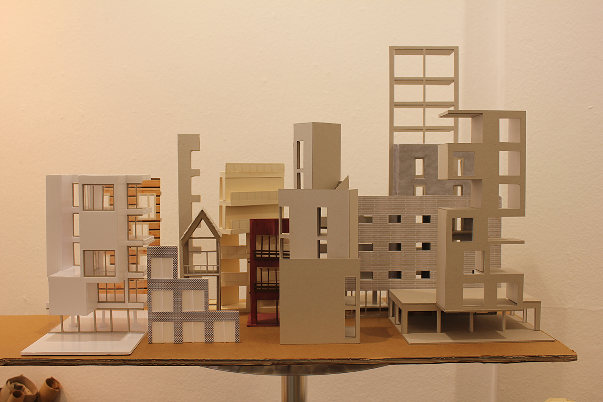 Eine Ansammlung verschiedener architektonischer Fassadenmodelle aus Pappe.
