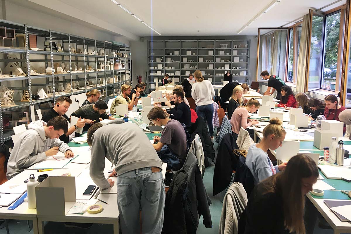 Viele Studierende arbeiten in einem Architektur-Atelier konzentriert an Modellen.