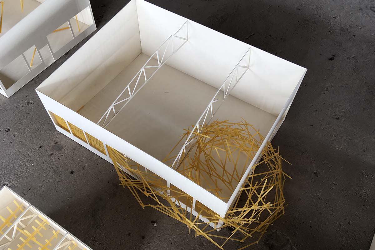 Weißes Architekturmodell, teilweise gefüllt mit gelben Spaghetti-Strukturen.