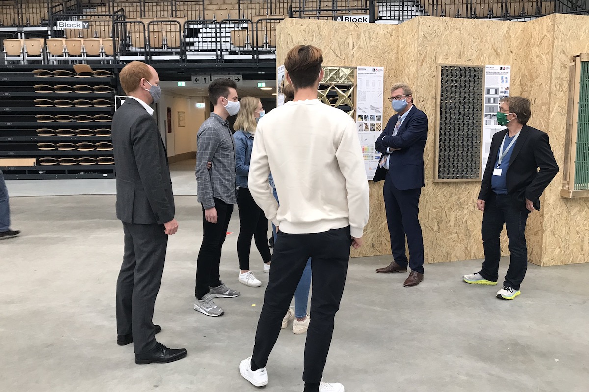 Studierende und Dozenten mit Masken im Gespräch vor den Exponaten.