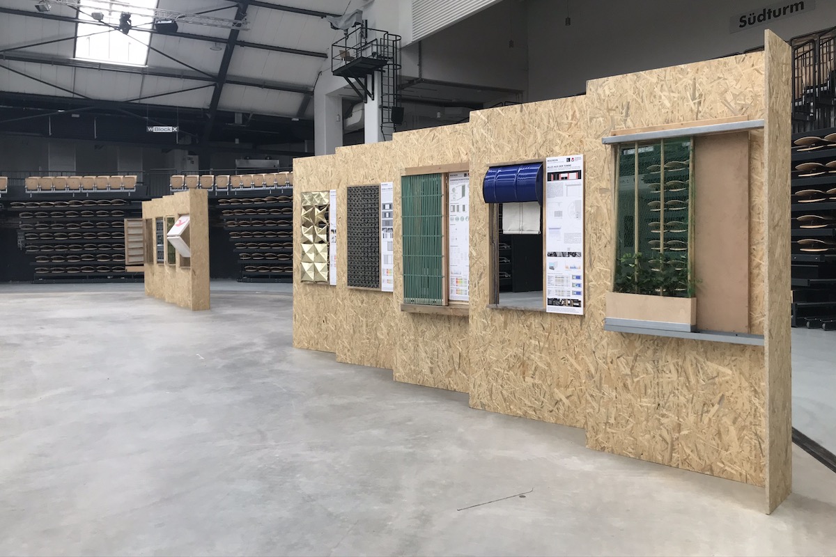 Reihe von detaillierten Fassadenmodellen an einer Wand aus OSB-Platten.