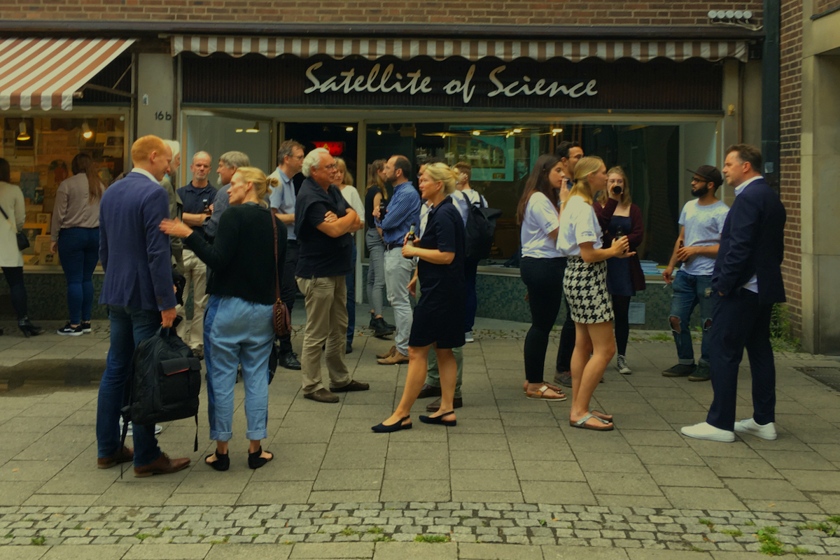 Menschengruppe unterhält sich tagsüber vor dem "Satellite of Science".