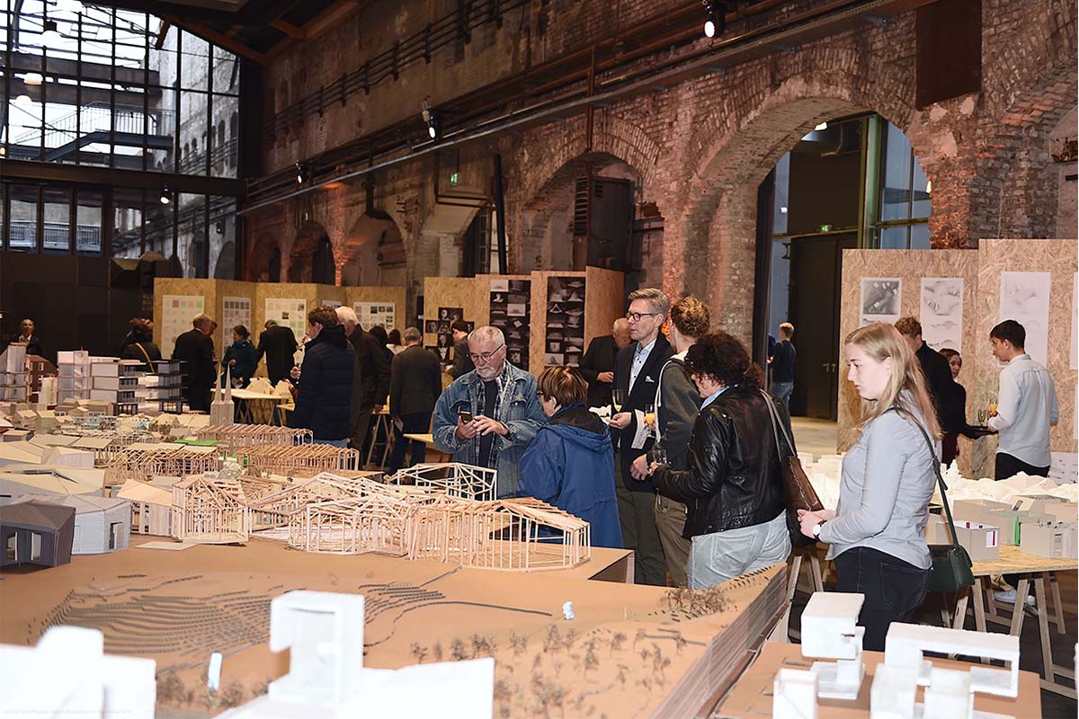 Ausstellungsgäste unterhalten sich vor Tischen mit Architekturmodellen.