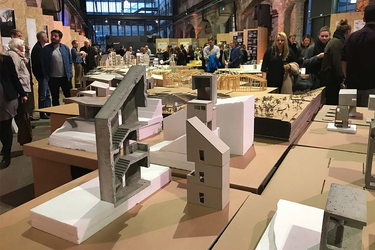 Verschiedene Architekturmodelle aus Beton und Pappe auf einem Ausstellungstisch.
