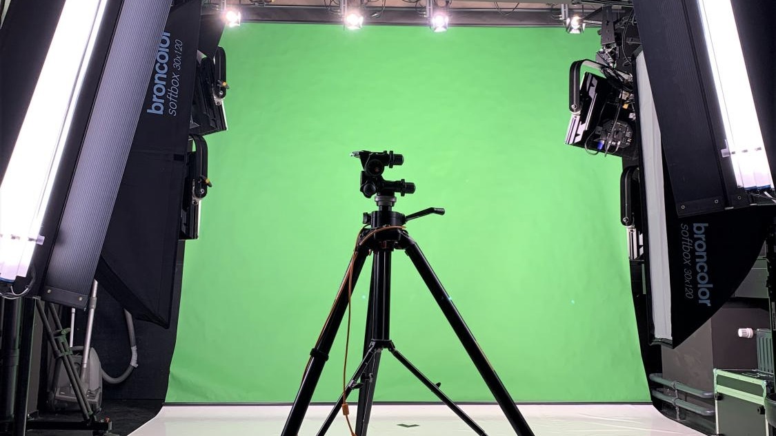 Stativ vor Greenscreen, wird von Studiolampen beleuchtet.