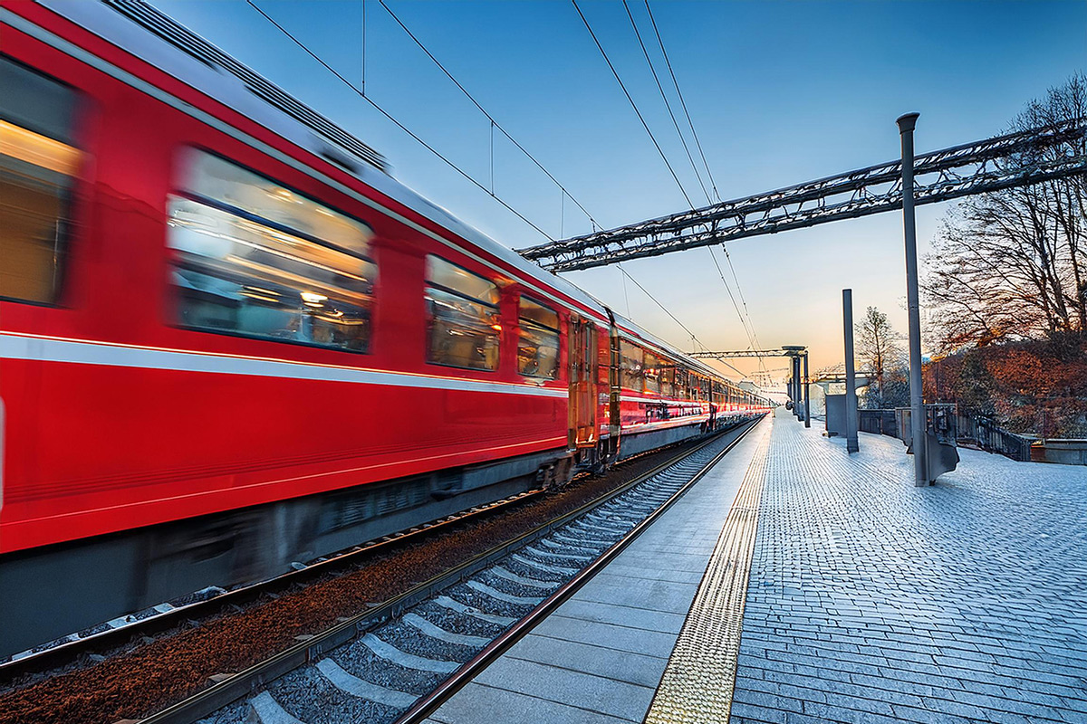 Anreise mit der Bahn Ein roter Regionalexpress der Deutschen Bahn fährt durch einen Bahnhof