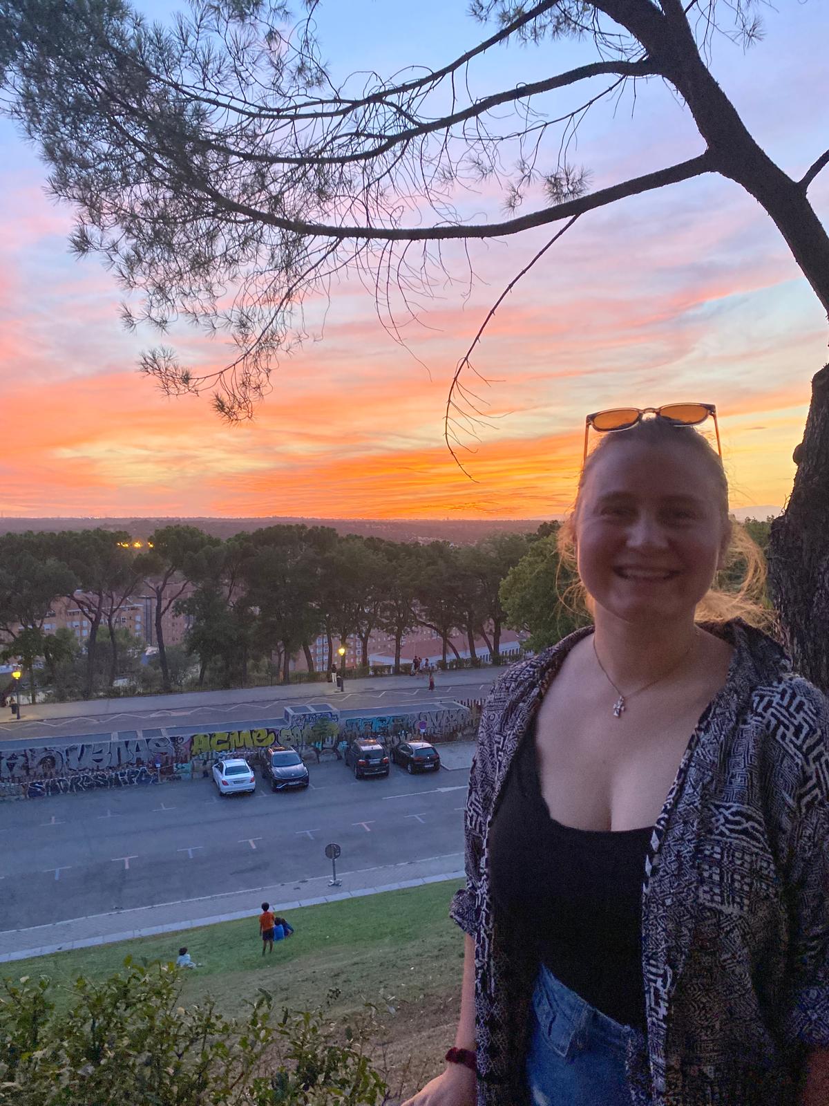 Smiling woman at sunset overlooking a city park area.
